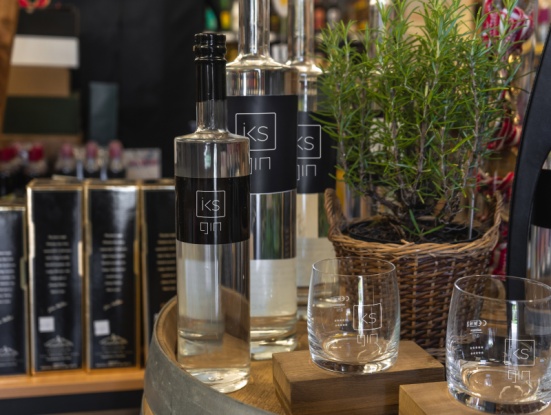 iks-Gin schön angerichtet auf einem Holzfass, Shop im Hintergrund